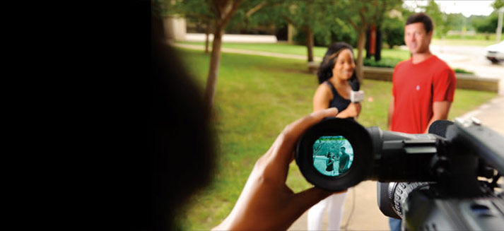 A student running a camera for a news interview