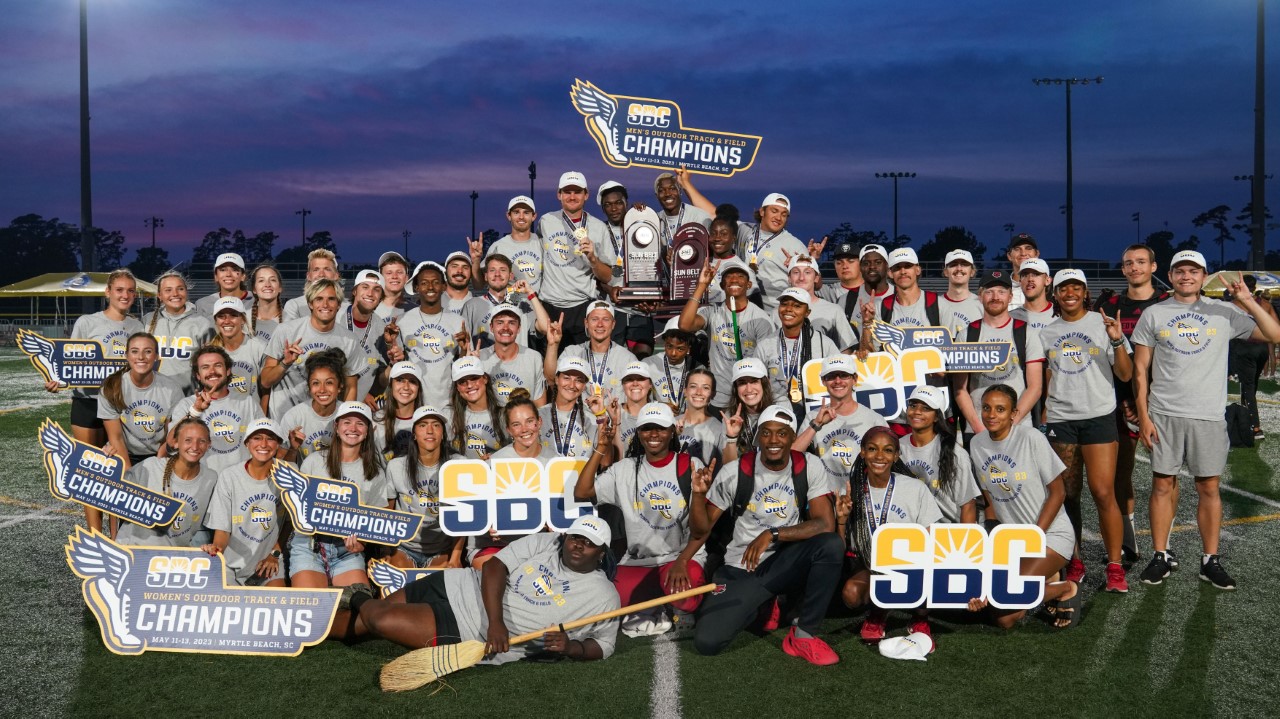 Photo of members of track teams with trophies